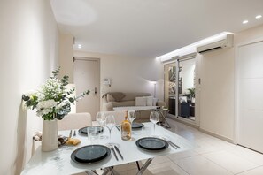A dining area with a table set for four, a vase of flowers, and a bottle of wine. - Apartment Le 46  by sur la mer (Cannes)