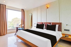 Une chambre d’hôtel avec un grand lit, une table de chevet, un miroir et une vue sur l’extérieur.