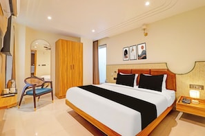 Une chambre d’hôtel avec un grand lit, une armoire en bois, un bureau avec une lampe et une chaise.