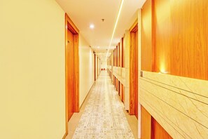 Un couloir d’hôtel avec des portes en bois et un tapis à motifs.