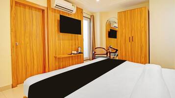 A hotel room with a bed, a television mounted on the wall, and a wardrobe.