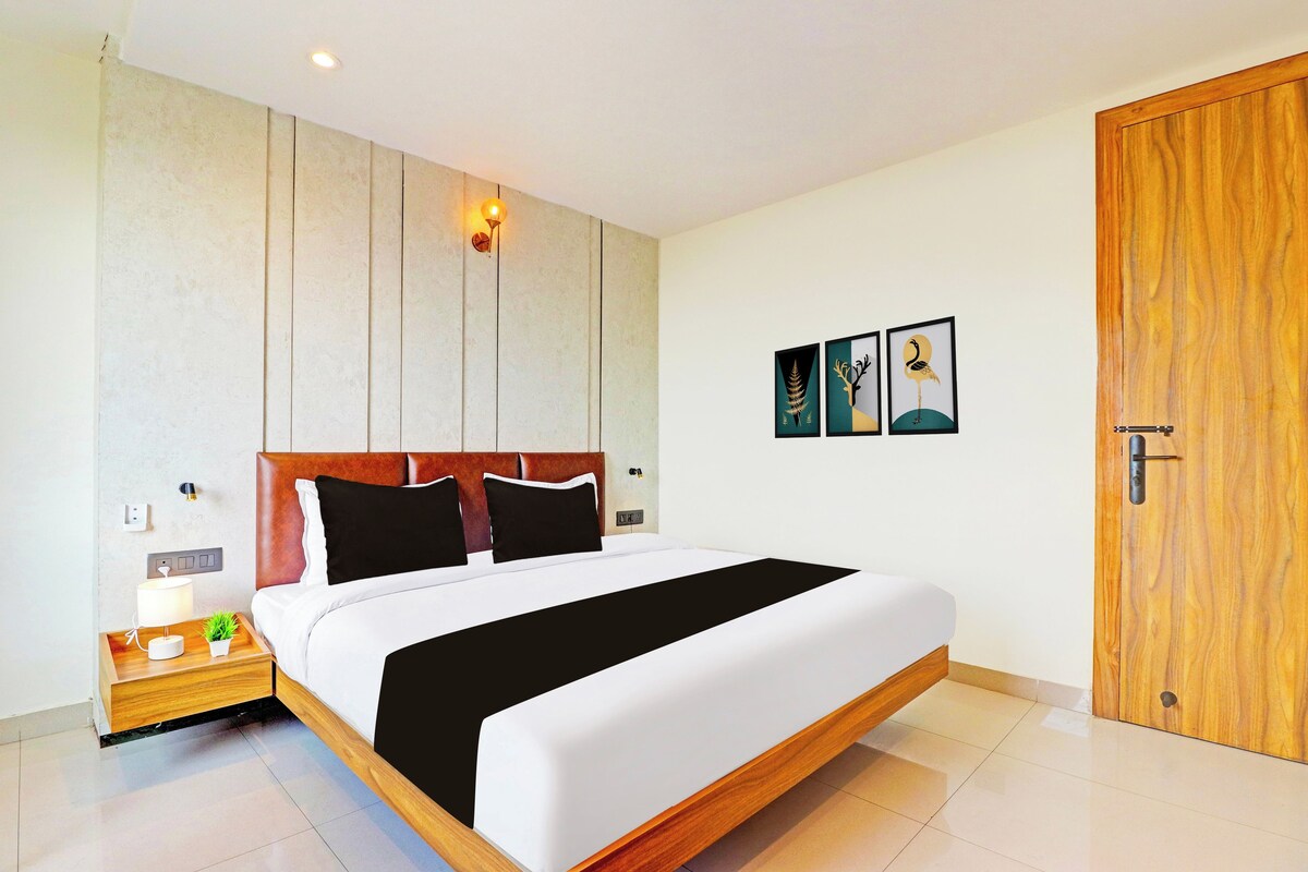 Una habitación de hotel moderna con una cama grande, cabecero de madera y una puerta de madera.