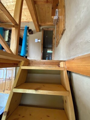 A wooden staircase leading to a room with a door and a window, and a wooden ceiling structure. - Serene 1-bedroom cottage in charming Bashisht perfect for relaxing (Bashisht)