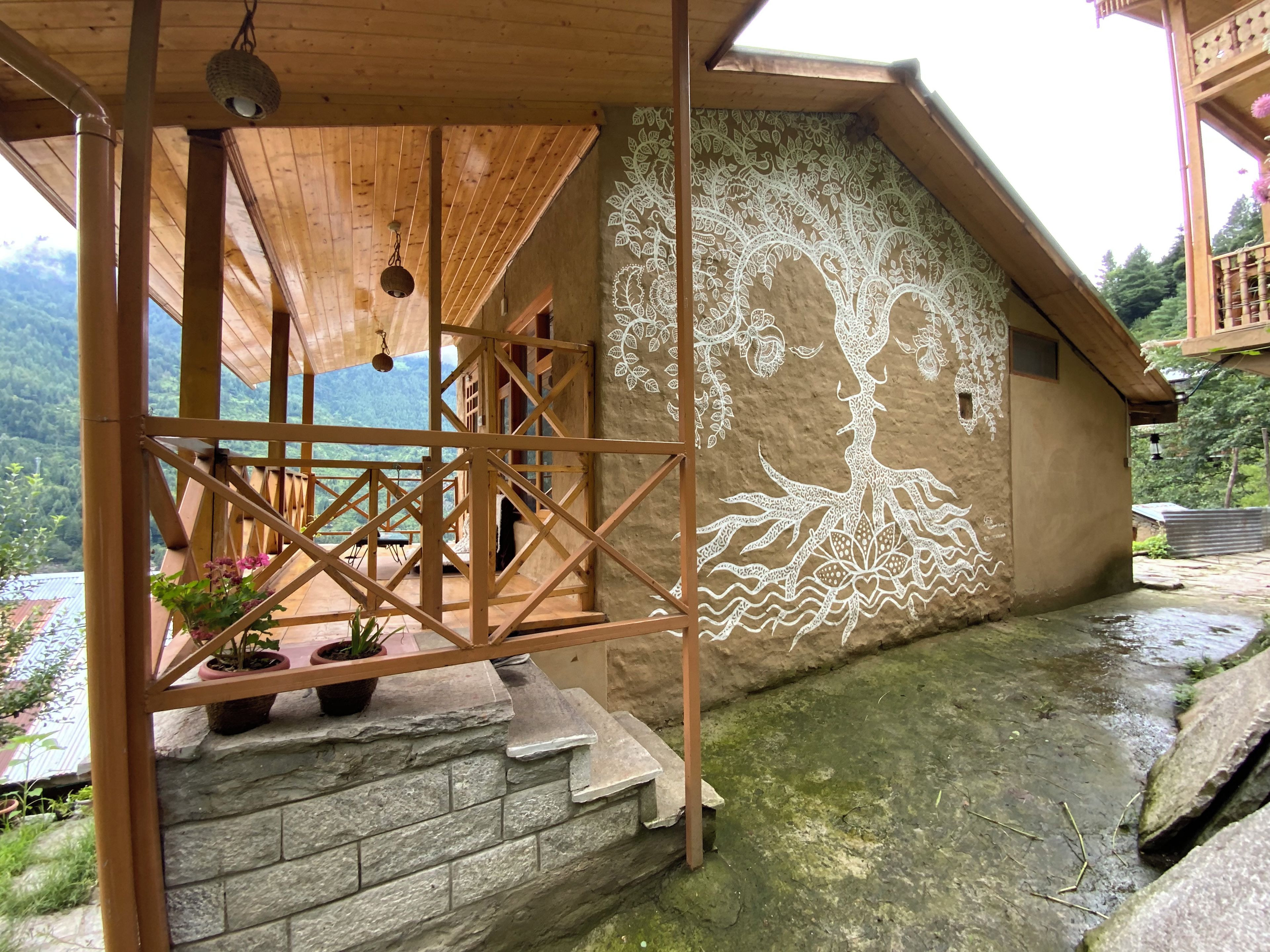 Une structure en bois dotée d’un escalier en pierre et ornée d’une fresque représentant un arbre avec ses racines.