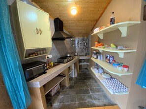 A kitchen with a stove, oven, and shelves with food items. - Serene 1-bedroom cottage in charming Bashisht perfect for relaxing (Bashisht)