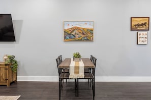 A dining area with a wooden table, chairs, and a central plant.