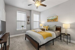 A bedroom with a bed, two bedside lamps, a ceiling fan, and a painting on the wall. - 4 Bd 3 Bath | Near TCU Campus (Fort Worth)