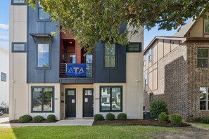 A multi-story building with a flat roof, a balcony with a blue banner, and a brick facade. - 4 Bd 3 Bath | Near TCU Campus (Fort Worth)