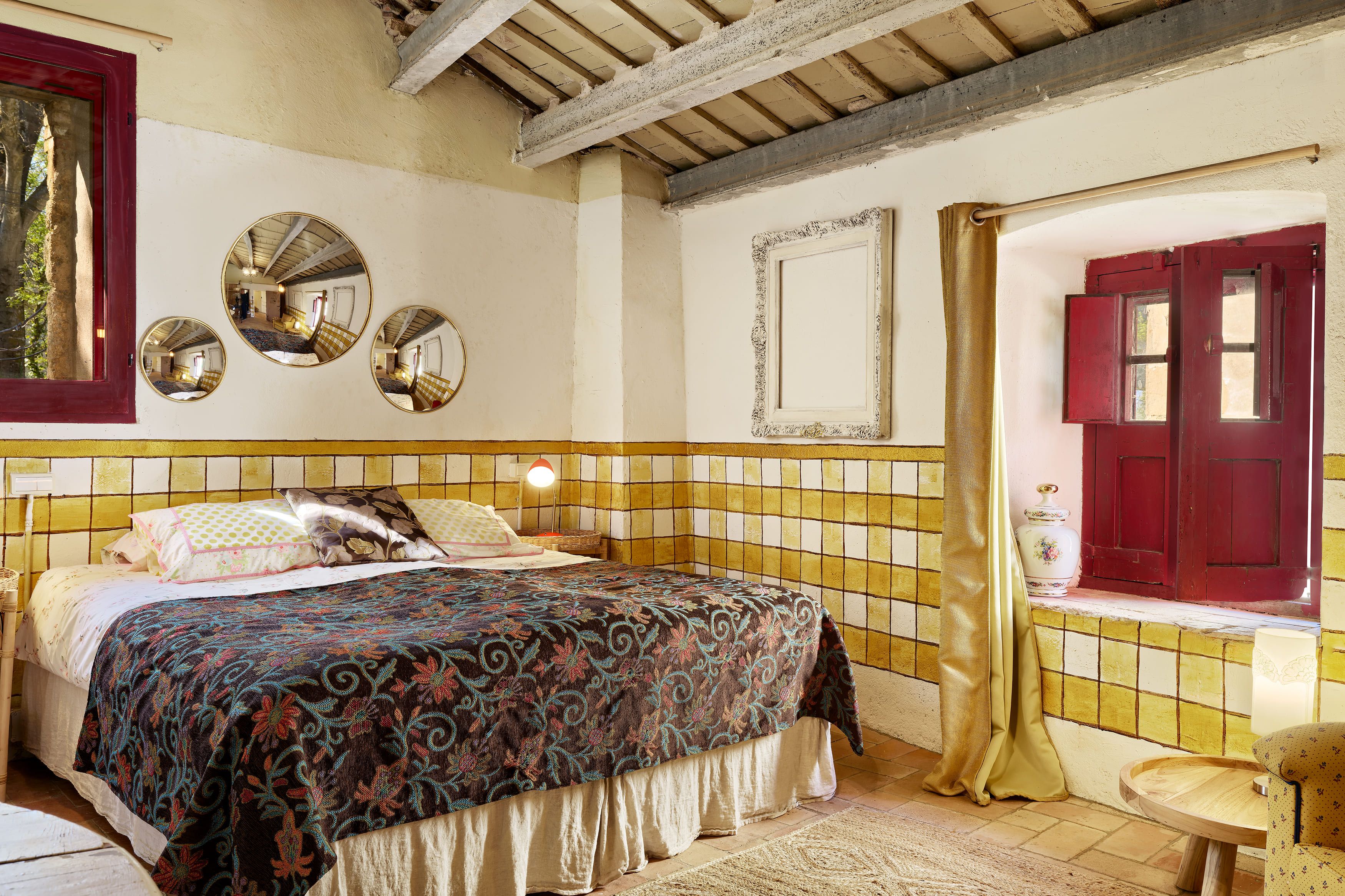 Ein Zimmer mit einem Bett, einem Stuhl, einem Spiegel und einer Tür.