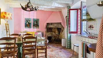 A rustic interior with a stone fireplace, wooden furniture, and a pink wall.