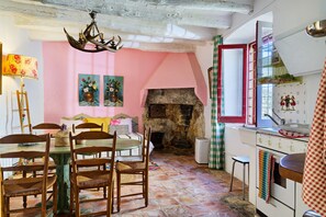 A rustic interior with a stone fireplace, wooden furniture, and a pink wall.
