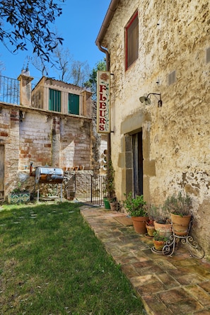Un bâtiment rustique avec une façade en pierre, une cheminée visible et une enseigne indiquant qu’il s’agit d’une boutique de fleurs.
