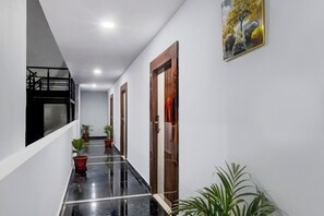 Un pasillo con suelo pulido, plantas en macetas y puertas que dan a habitaciones.