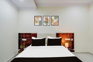Habitación de hotel con una cama, dos mesitas de noche, un teléfono de pared y tres obras de arte enmarcadas.