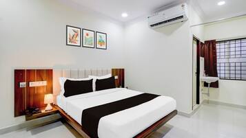 Une chambre d’hôtel comprenant un lit, une table de chevet, une lampe, un appareil de climatisation et une fenêtre avec des rideaux.