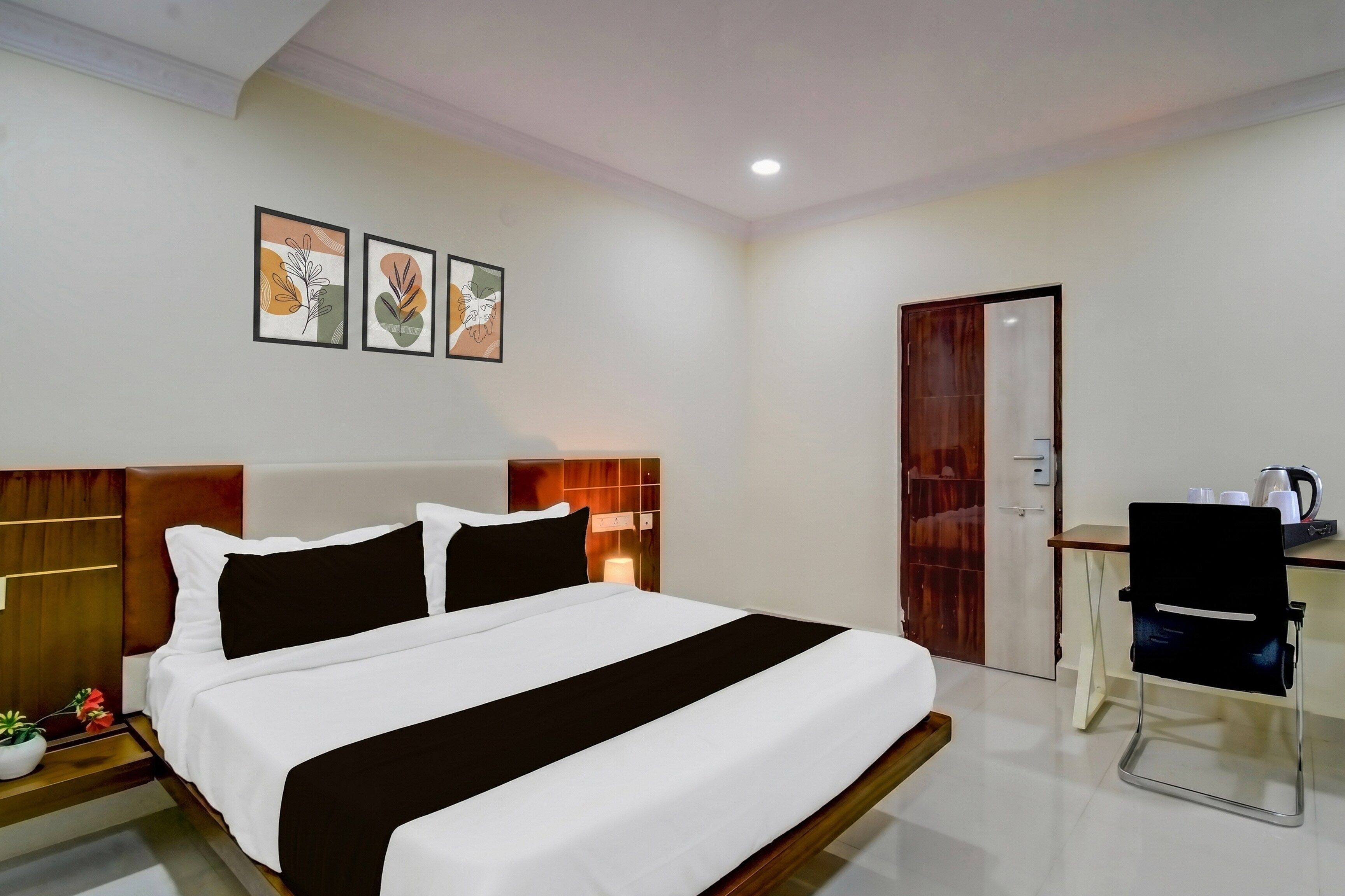A modern hotel room with a large bed, a desk, and a wardrobe.