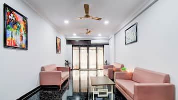 A modern living room with two sofas, a coffee table, and ceiling fans.