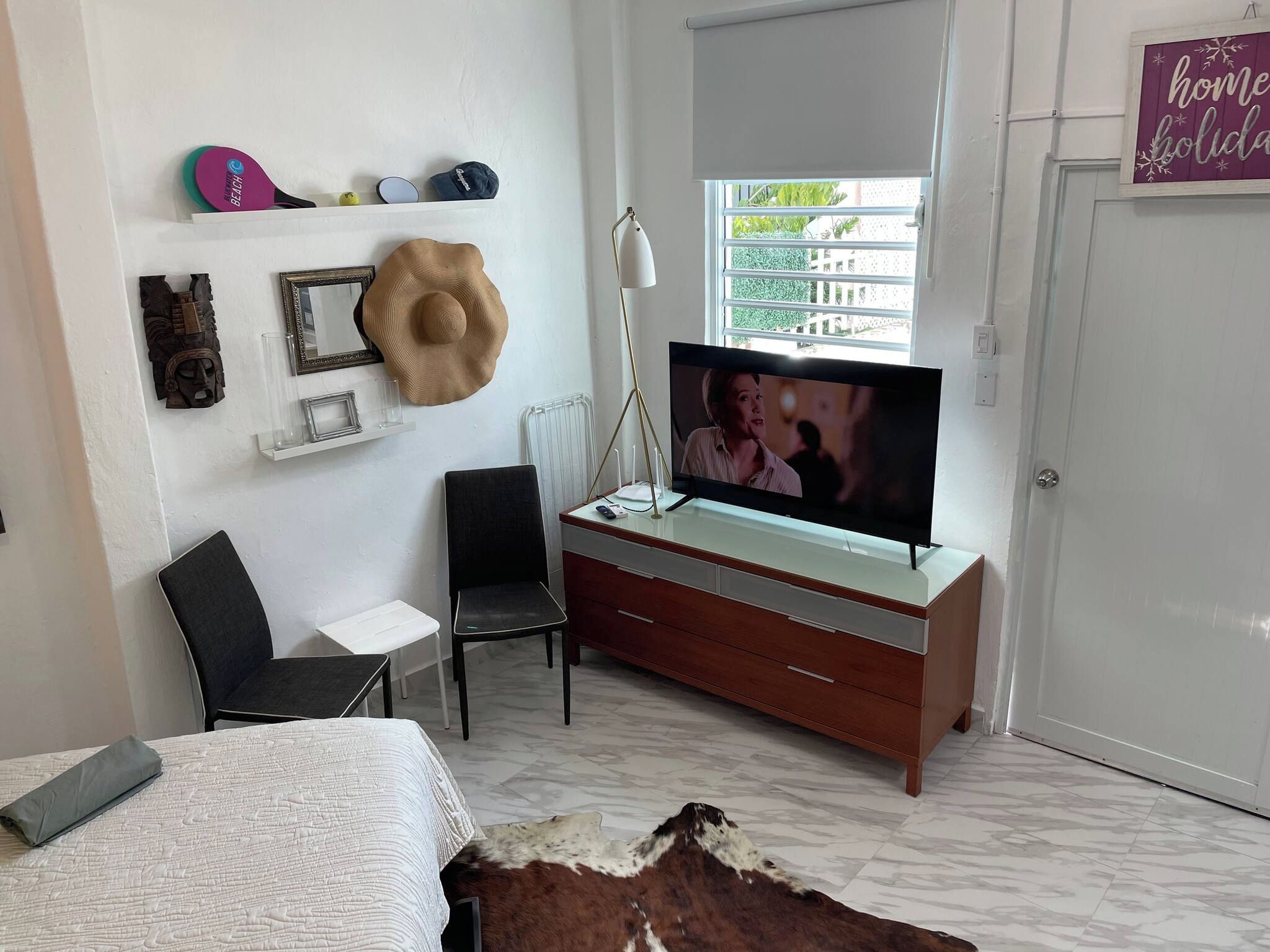 A bedroom with a bed, a TV, a desk, a chair, and a cowhide rug.