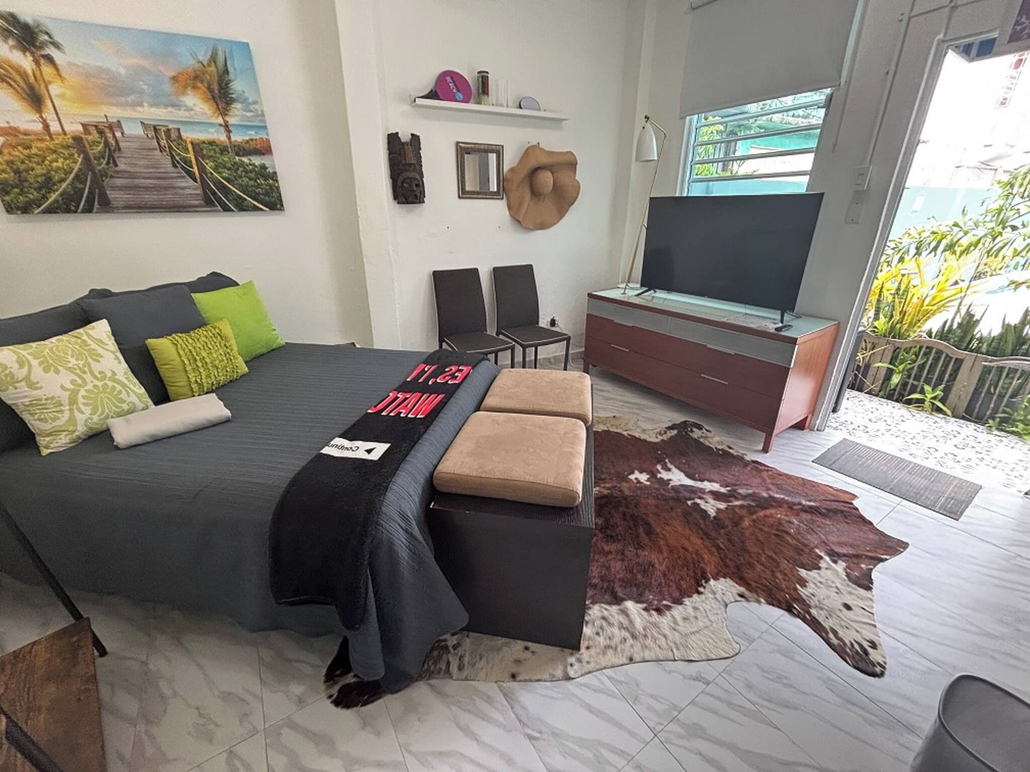 Une chambre à coucher avec un lit, une télévision, un bureau et une vue sur l’extérieur.