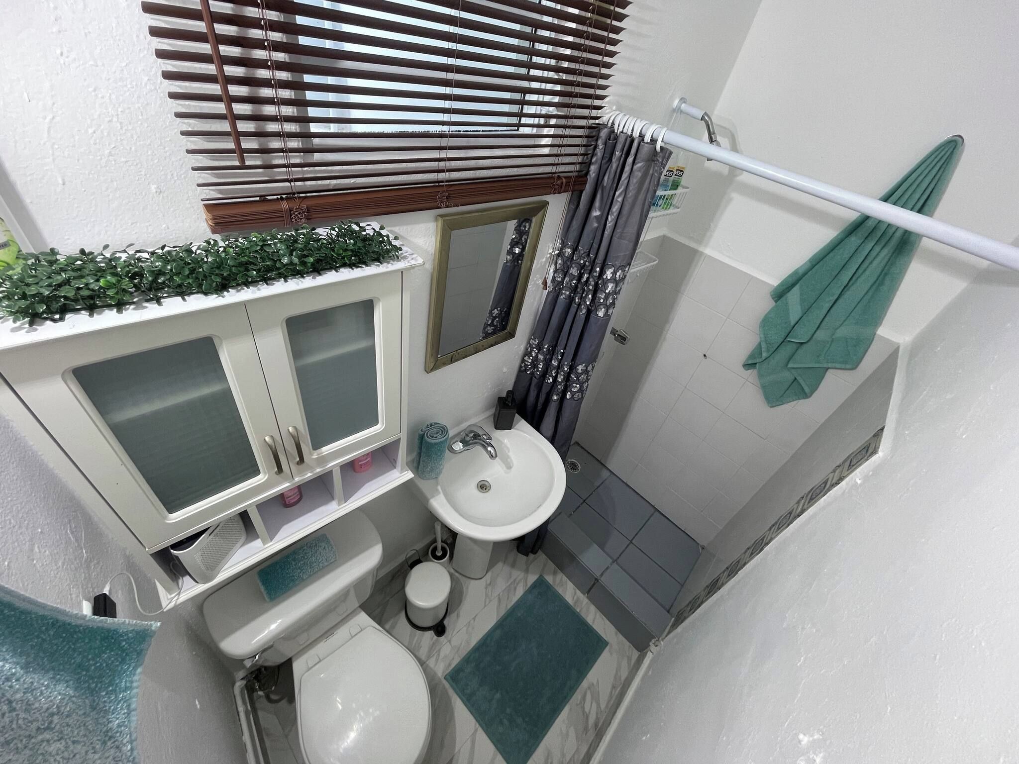 A compact bathroom with a toilet, sink, and shower area.
