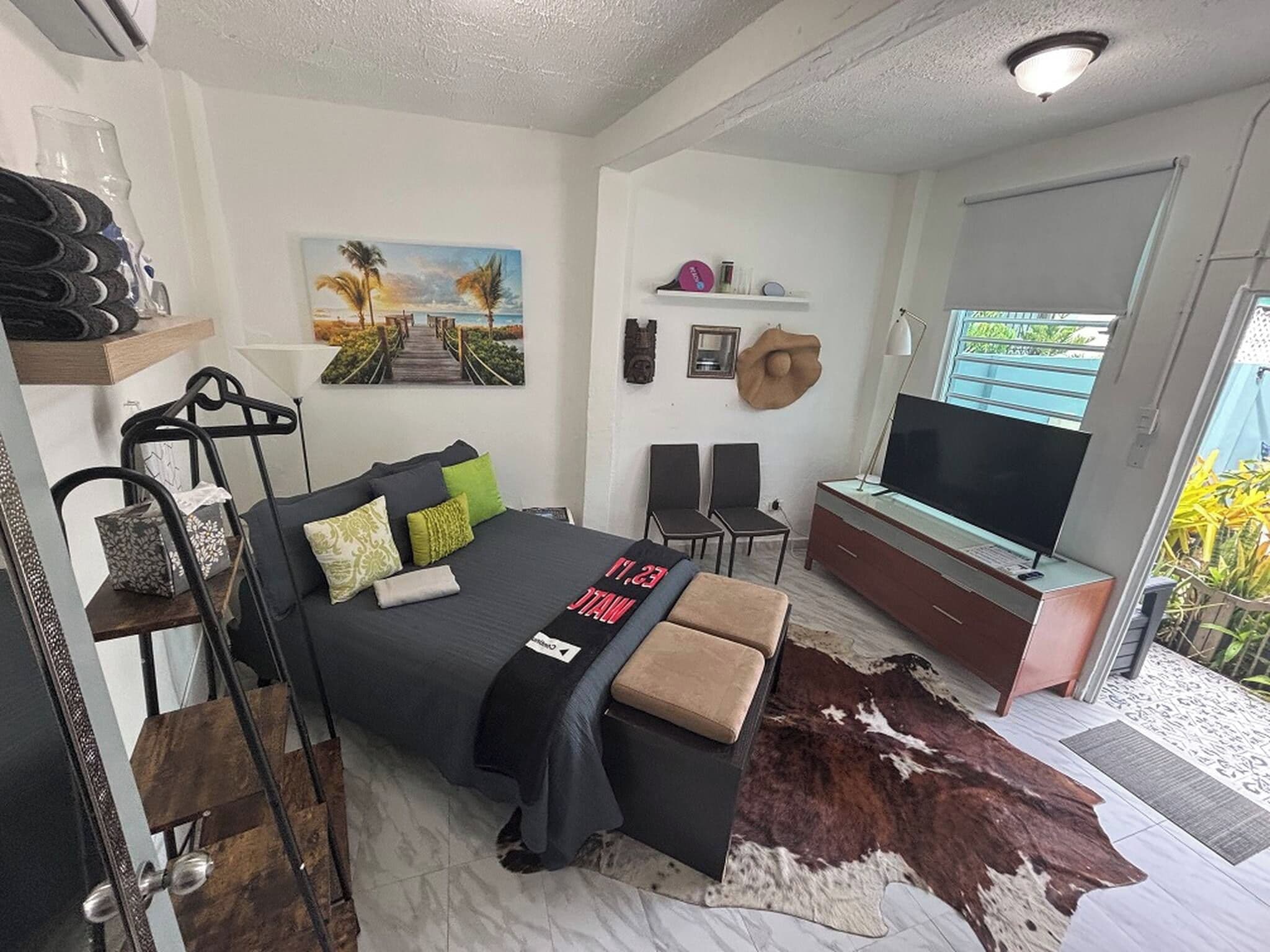 A bedroom with a bed, a TV, a desk, and a cowhide rug.