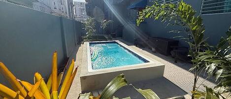 Una piscina de forma rectangular, rodeada por una solana de concreto y delimitada por muros.