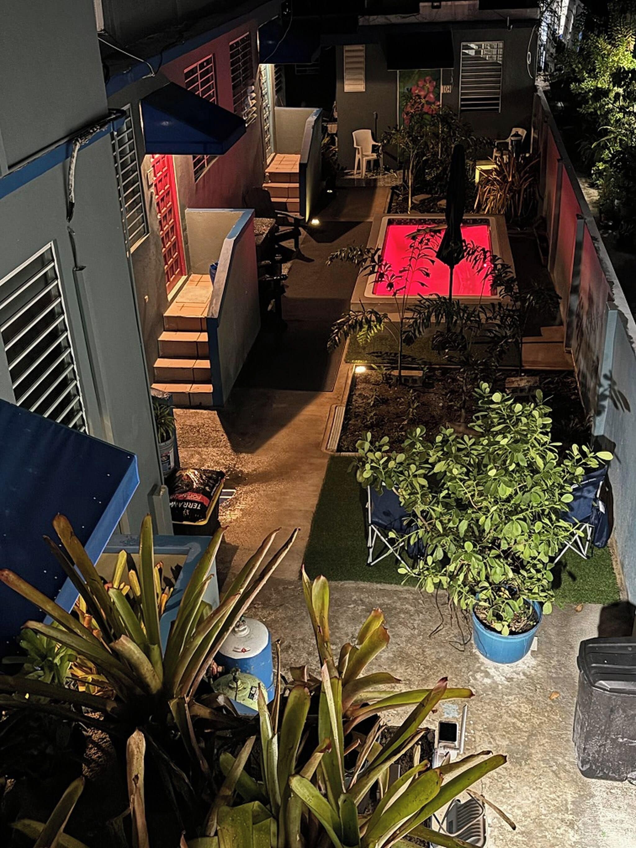A courtyard with a pool, potted plants, and outdoor furniture.