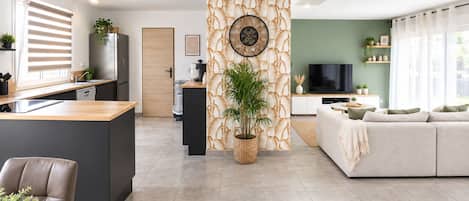 Un espacio habitable moderno con cocina, comedor y zona de estar con sofá y televisor.