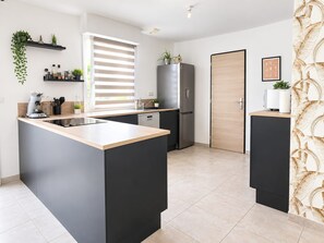 A modern kitchen with a central island, a refrigerator, and a sink. - La Parenthèse de Chaumes  Proche de la mer  T3 (Chaumes-en-Retz)