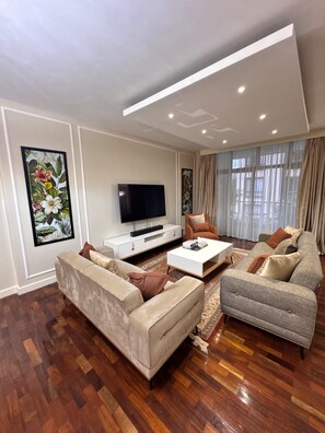 A modern living room with a flat-screen TV, two sofas, a coffee table, and artwork on the walls. - 2-bedroom apartment in Kilimani,Nairobi with fitness room access and swimming (Nairobi)