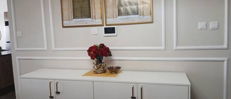 Un armario blanco con dos puertas y un jarrón con flores rojas encima.