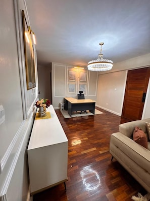 A spacious room with a white console table, a wooden floor, a beige sofa, and a chandelier. - 2-bedroom apartment in Kilimani,Nairobi with fitness room access and swimming (Nairobi)