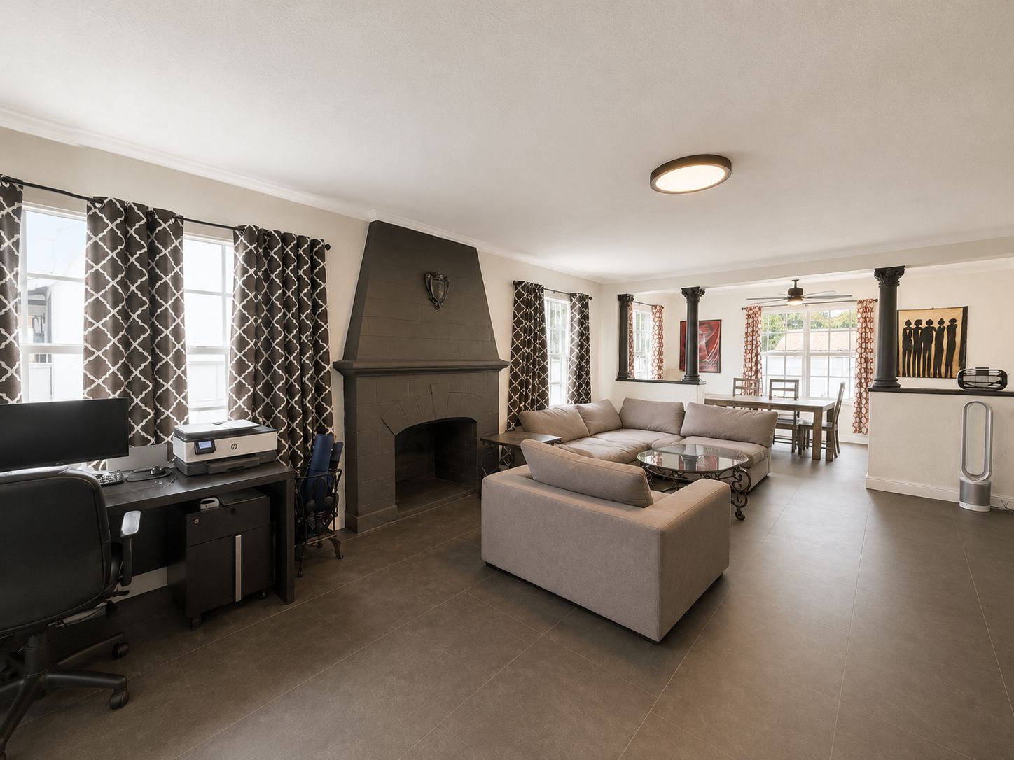 Ein modernes Wohnzimmer mit Kamin, einer Couch, einem Essbereich und einem Arbeitsplatz mit Computer.