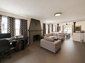 Een moderne woonkamer met een open haard, een bank, een eethoek en een werkplek met een computer.