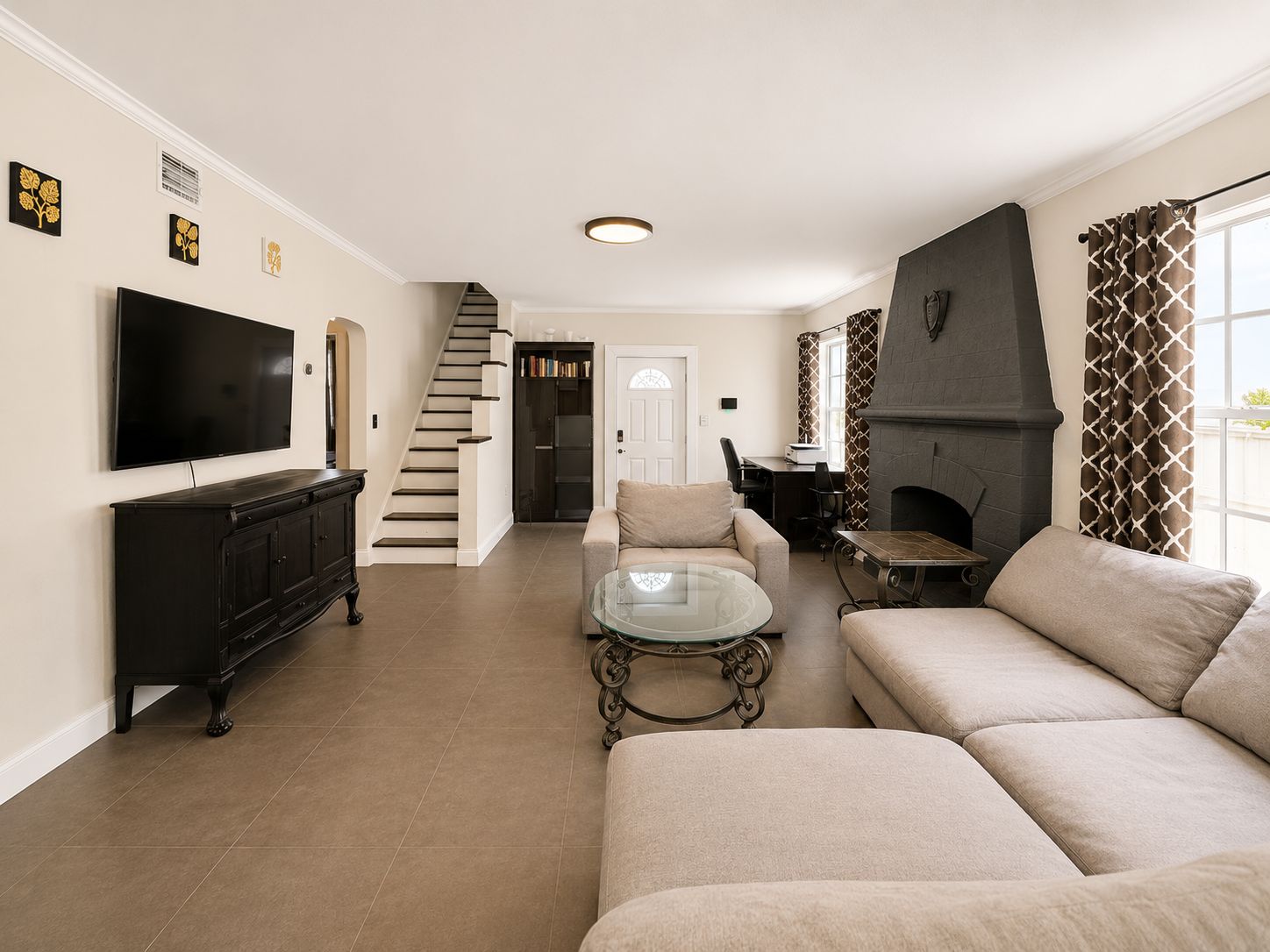 Una sala de estar moderna con un televisor de pantalla plana, una chimenea y una escalera que conduce a otra habitación.