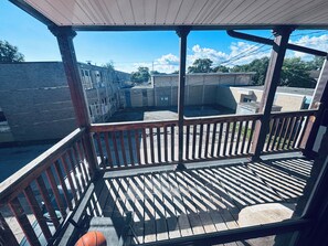 Un espacio al aire libre techado con una terraza de madera, un balón de baloncesto y vistas a un barrio residencial.
