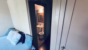 Et soveværelse med seng, garderobeskab og udsigt til et badeværelse med toilet og håndvask.