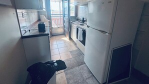 Et kompakt køkken med køleskab, ovn og en lille bordplade.