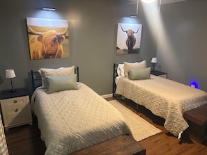 Een slaapkamer met twee bedden, nachtkastjes, een lamp en wanddecoratie.