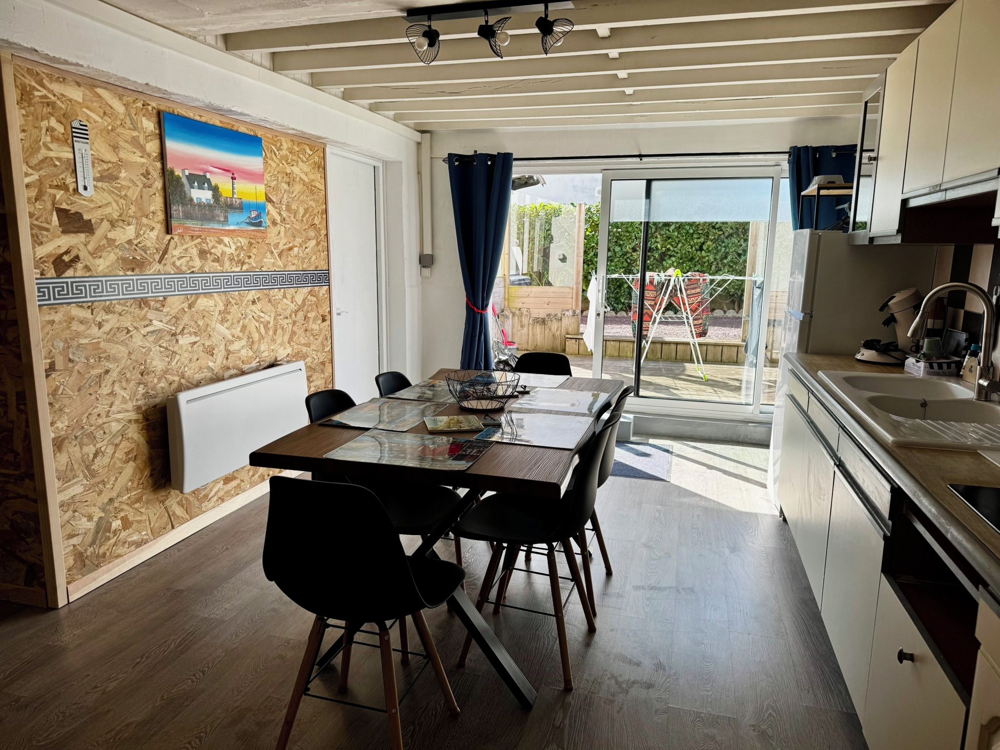 Un espace repas comprenant une table, des chaises et donnant sur l’extérieur.