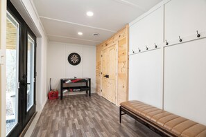 Ein Zimmer mit einer Sitzbank, einer Dartscheibe, einem Tisch mit einem roten Gegenstand und einem hölzernen Kleiderschrank mit Haken.