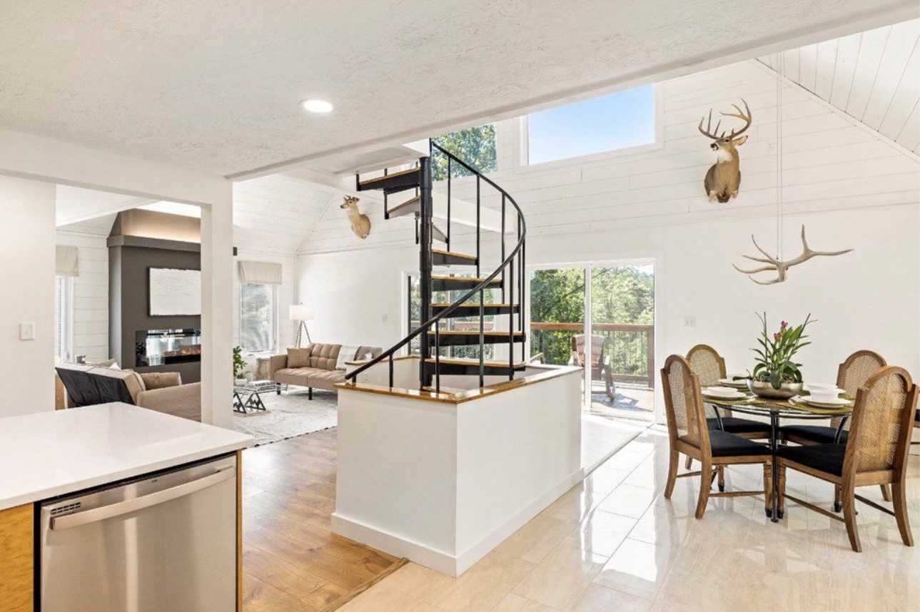 A spacious living area with a central island, a spiral staircase, and a dining area with chairs and a table.