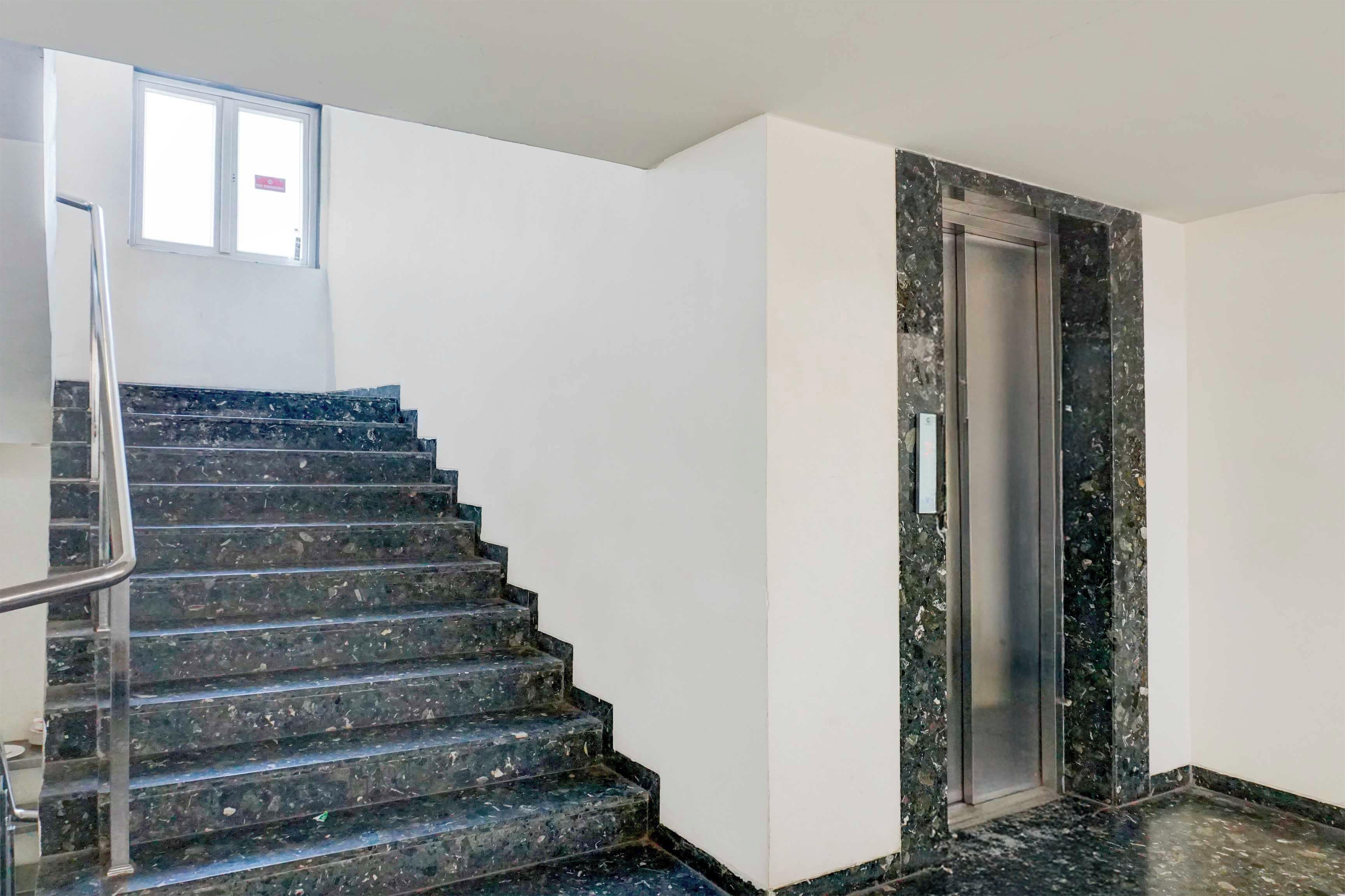 Una escalera con barandilla que lleva a un ascensor.