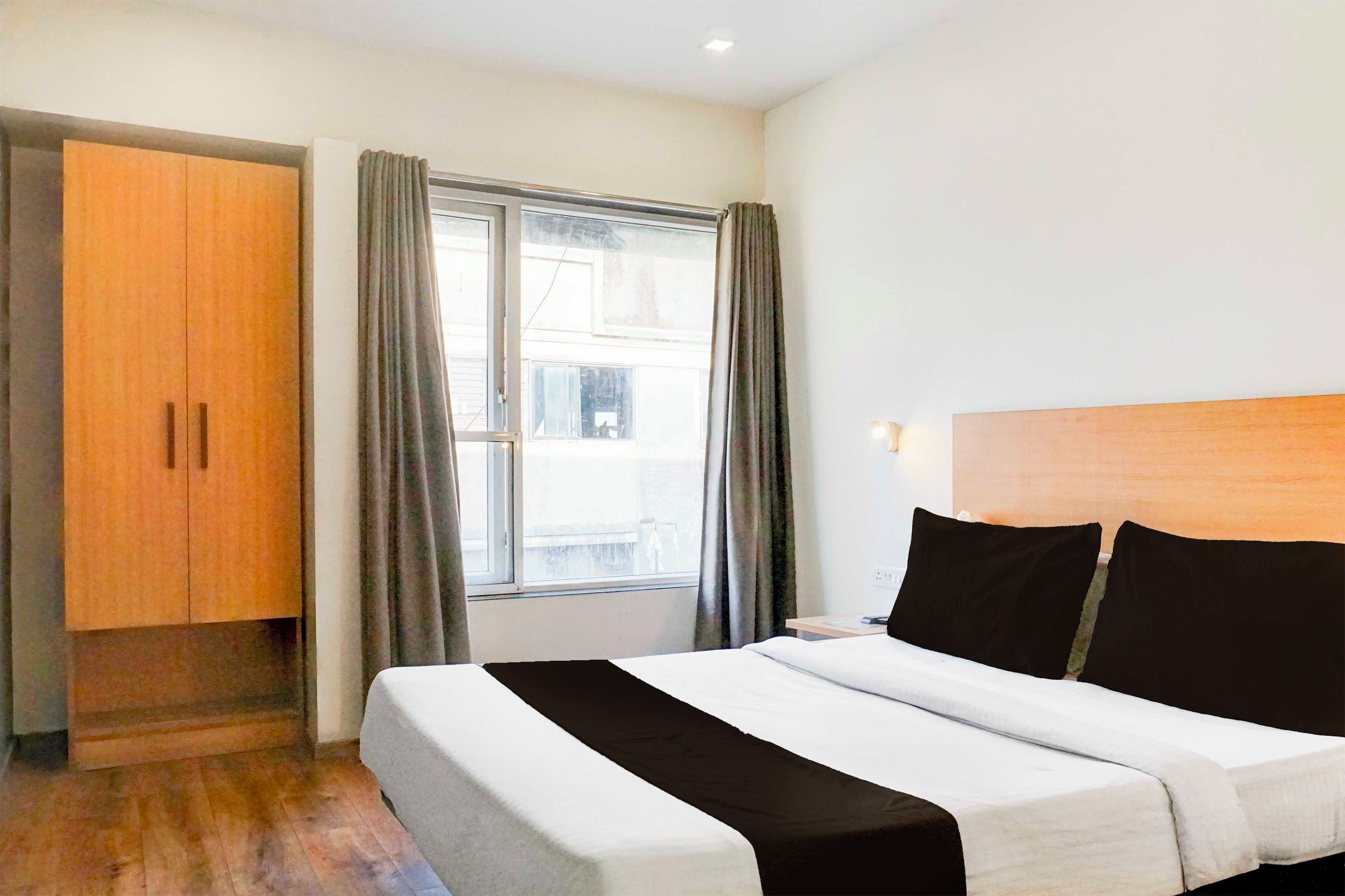 Een hotelkamer met een bed, een kledingkast, een raam met gordijnen en uitzicht op buiten.