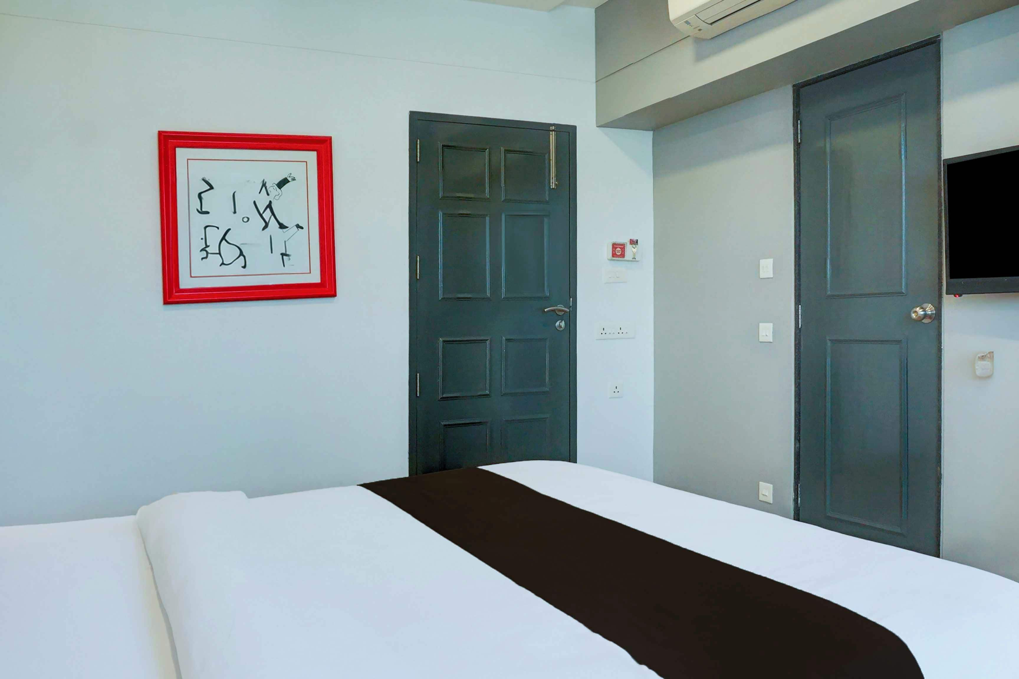 Quarto de hotel com cama, porta e quadro na parede.