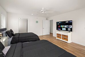 A bedroom with two beds, a ceiling fan, a TV on a white cabinet, and a door leading to another room. -  Cozy1 bedroom Apt 1.5 bath in wonderful Ocean City near28st 2mints to boardwalk (Ocean City)