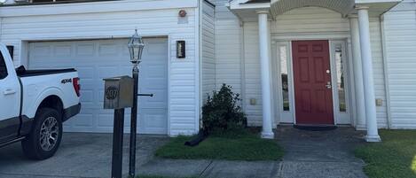 A two-story white building with a red door, a mailbox, and a parked white pickup truck.