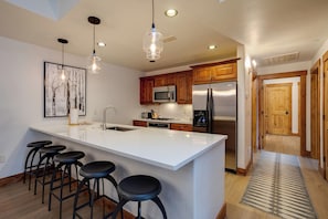 Gather around the sleek kitchen island with seating for five, where you can prep meals with modern appliances and gleaming white countertops in this inviting, light-filled space. - EL5109 | Private Hot Tub | Winter Shuttle | Air Chilling | Pool (Steamboat Springs)