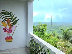 A balcony with a painted floral design, a view of a lush landscape, and a metal trellis. - Stylish Sanctuary: Mountain & Sea Views at Nya’s Place from Your Private Balcony (Tower Isle)