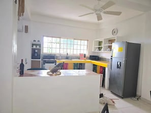 A kitchen with a stove, refrigerator, and a window with blinds. - Stylish Sanctuary: Mountain & Sea Views at Nya’s Place from Your Private Balcony (Tower Isle)